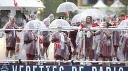 Atlet Denmark menggunakan payung dan jas hujan tetap bersemangat saat mengikuti parade acara pembukaan Olimpiade 2024 di Paris, Sabtu (27/7/2024). (Steph Chambers/Pool Photo via AP)