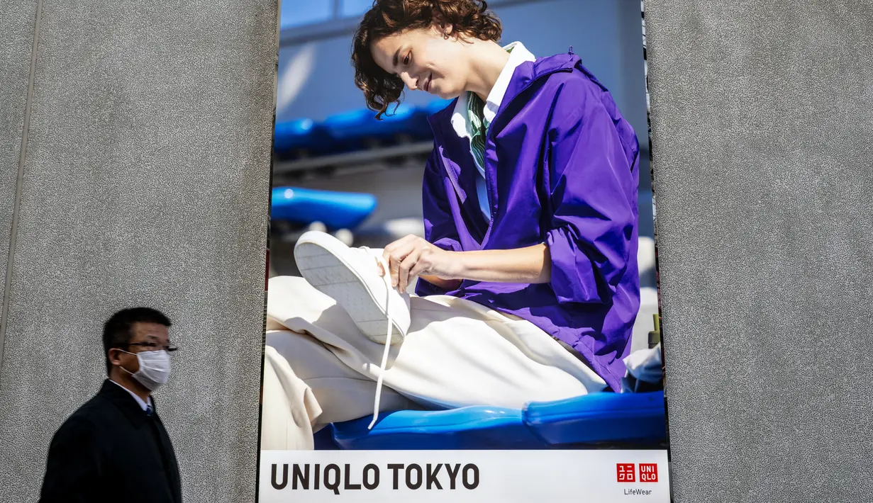 Seorang pria berjalan melewati iklan di pintu masuk toko Uniqlo yang dioperasikan oleh Fast Retailing Jepang di Tokyo, Rabu (11/1/2023). Berdasarkan pernyataan resmi Fast Retailing, rencana kenaikan gaji mencakup pekerja di kantor pusat maupun di toko cabang. (Philip FONG / AFP)