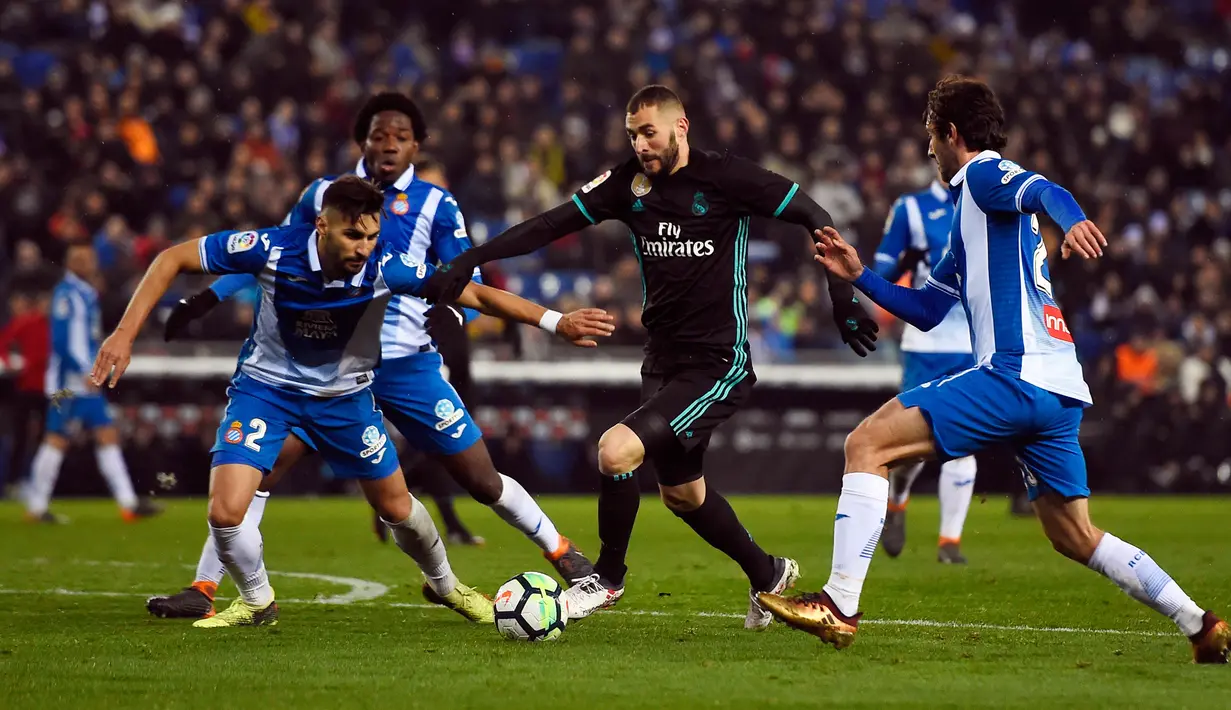 Pemain Real Madrid, Karim Benzema berebut bola dengan pemain Espanyol Marc Granero dan Granero pada pertandingan pekan ke-26 La Liga, di Stadion RCDE, Selasa (27/2). Real Madrid harus menyerah dari Espanyol dengan skor akhir 0-1. (Josep LAGO / AFP)