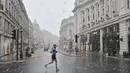 Warga yang sedang olahraga harian melintasi Regent Street di London di tengah salju saat ibu kota Inggris mengalami hujan salju yang jarang terjadi pada Minggu (24/1/2021). Hujan salju langka itu membawa kegembiraan di tengah penguncian atau penutupan wilayah (lockdown) nasional (JUSTIN TALLIS/AFP)