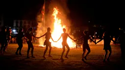 Sejumlah orang mengitari kobaran api saat mengikuti tradisi malam San Juan's (Saint John) di Gijon, Spanyol, (24/6). Malam San Juan juga dilakukan dengan berenang saat musim panas tiba. (REUTERS/Vincent West)