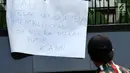 Salah satu peserta aksi melihat kertas pesan saat berunjuk rasa di depan Kedubes Malaysia, Jakarta, Senin (21/8). Aksi ini terkait kasus terbaliknya bendera Merah Putih pada buku panduan pelaksanaan SEA Games 2017. (Liputan6.com/Helmi Fithriansyah)