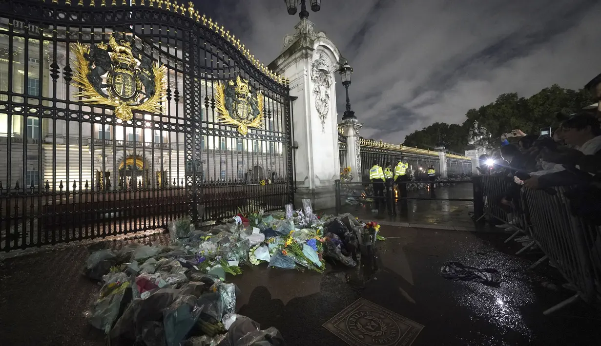 Karangan bunga ditinggalkan di luar Istana Buckingham di pusat kota London, menyusul pengumuman meninggalnya Ratu Elizabeth II, Kamis, 8 September 2022. (Yui Mok/PA via AP)