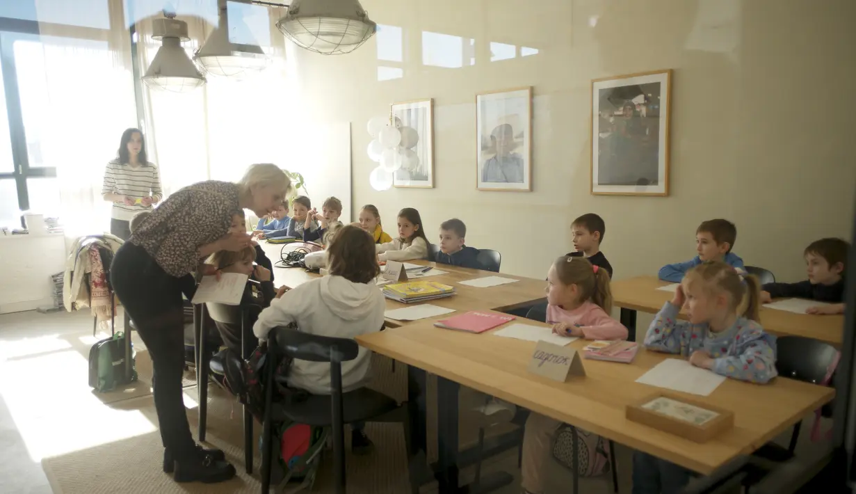 Guru Ukraina Tatyana Gubskaya (tengah) mengajar kelas anak-anak dari Ukraina di Berlin, Jerman, Senin (21/3/2022). Empat puluh anak pengungsi Ukraina memulai hari pertama sekolah dasar di Berlin hanya beberapa minggu setelah mereka melarikan diri dari perang. (AP Photo/Markus Schreiber)