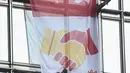 Alain Robert yang dijuluki 'French Spiderman' mengibarkan bendera China dan Hong Kong di Cheung Kong Center, Hong Kong, Jumat (16/8/2019). Alain membentangkan spanduk perdamaian ketika pusat bisnis itu mengalami masalah internal dan maraknya demonstrasi. (Lillian SUWANRUMPHA/AFP)
