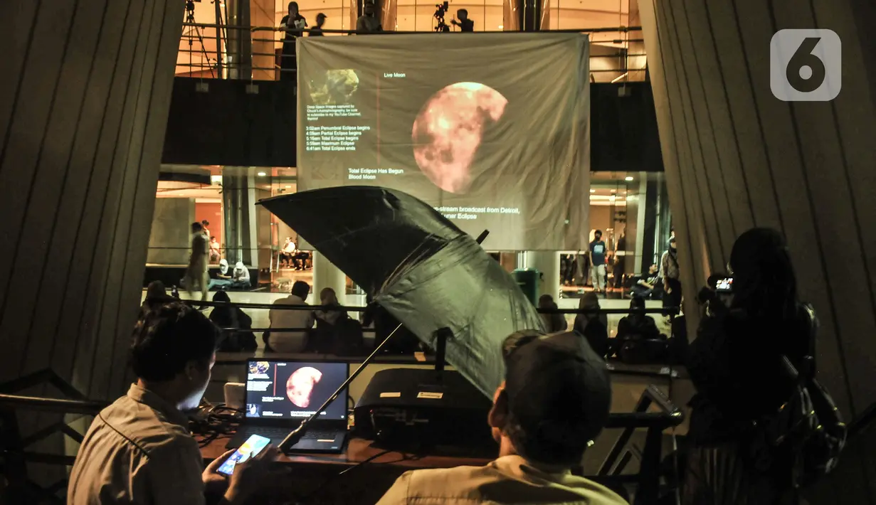 Warga menyaksikan fenomena gerhana bulan total atau Bloodmoon di Taman Ismail Marzuki, Jakarta Pusat, Selasa (8/11/2022). Warga tetap antusias mendatangi Taman Ismail Marzuki untuk menyaksikan fenomena Gerhana Bulan Total yang digelar oleh Planetarium dan Obersevasi Jakarta (POJ) meski turun hujan dan hanya melihat dari siaran langsung (streaming). (merdeka.com/Iqbal S Nugroho)