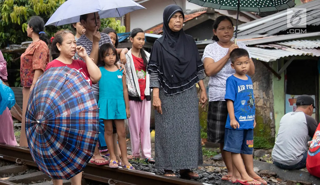 Warga melihat proses evakuasi KRL yang anjlok di kawasan Kebon Pedes, Bogor, Jawa Barat, Minggu (10/3). Penanganan KRL anjlok dilakukan dengan menggunakan crane yang didatangkan dari Bandung. (Liputan6.com/Immanuel Antonius)