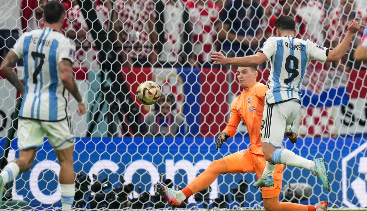 <p>Penyerang Argentina, Julian Alvarez menendang bola melewati kiper Kroasia Dominik Livakovic untuk mencetak gol kedua timnya pada pertandingan semifinal Piala Dunia 2022 di Stadion Lusail di Lusail, Qatar, Rabu (14/12/2022). Argentina berhasil lolos ke final setelah menang telak atas Kroasia dengan skor 3-0. (AP Photo/Petr David Josek)</p>
