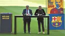 Tak sampai di situ, ketika memasuki lapangan, Dani Alves malah melepas sendal jepitnya alias nyeker. Bahkan hal tersebut bertahan hingga momen teken kontrak di tengah lapangan bersama Joan Laporta (kiri). (AFP/Pau Barrena)