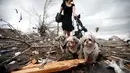 Seorang wanita membawa tiga anjing diantara puing-puing rumah yang rusak akibat Tornado di New Orleans, AS (7/2). (Sean Gardner/Getty Images/AFP)