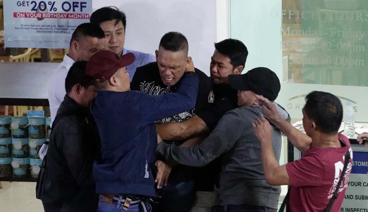 Polisi menangkap pelaku penyenderaan Alchie Paray (tengah) saat sedang berbicara kepada awak media di V-Mall, Manila, Filipina, Senin (2/3/2020). Alchie Paray tidak sempat memberikan banyak pernyataan karena polisi langsung menjauhkannya dari awak media. (AP Photo/Aaron Favila)