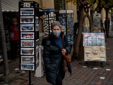 Seorang perempuan dengan masker berjalan di dekat Monastiraki square, pusat kota Athena, Yunani, Rabu (29/12/2021). WHO memperingatkan Organisasi Kesehatan Dunia (WHO) memperingatkan lonjakan kasus Covid-19 varian Omicron dapat menyebabkan fasilitas kesehatan kewalahan. (Angelos Tzortzinis/AFP)