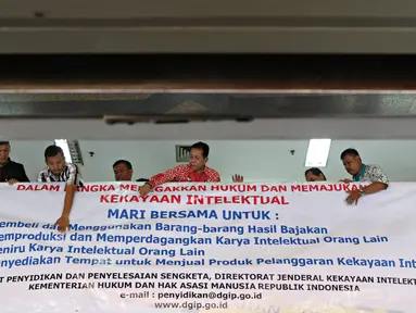 Petugas memasang spanduk sosialisasi peningkatan kesadaran untuk menghormati hasil karya intelektual di salah satu pusat perbelanjaan elektronik di Mangga Dua, Jakarta, Rabu (18/5).(Liputan6.com/Immanuel Antonius)