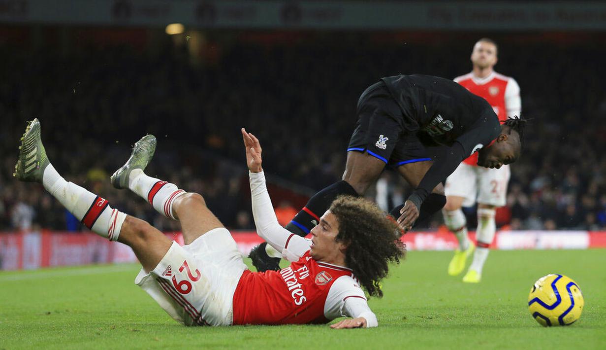 Gelandang Arsenal, Matteo Guendouzi, terjatuh saat berebut bola dengan pemain Crystal Palace, Wilfried Zaha, pada laga Premier League 2019 di Stadion Emirates, Minggu 927/10). Kedua tim bermain imbang 2-2. (AP/Leila Coker)