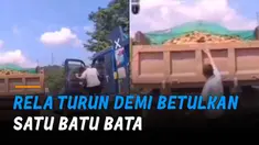 Seorang sopir truk biru tiba-tiba turun saat menunggu lampu merah untuk membetulkan muatan diduga batu bata di truk oranye.
