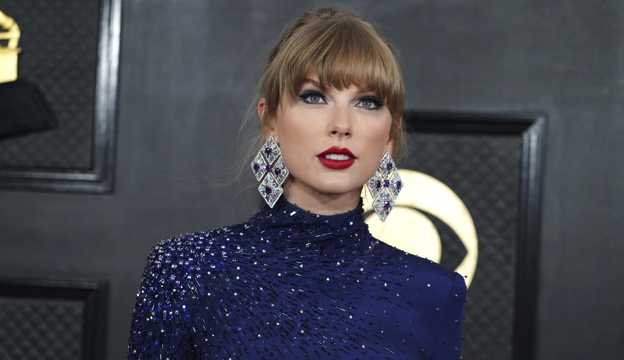 Taylor Swift tiba menghadiri ajang Grammy Awards 2023 di Crypto.com Arena, Los Angeles, AS, Senin (6/2/2023) pagi waktu Indonesia. Penyanyi berusia 33 tahun itu tampil memesona dengan gaun crop top lengan panjang warna biru dihiasi aksen glitter dari Roberto Cavalli. (Photo by Jordan Strauss/Invision/AP)