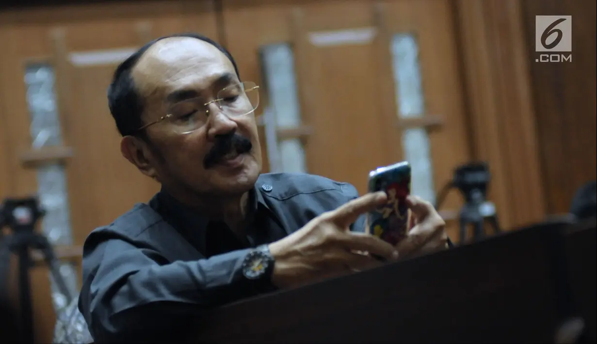 Terdakwa perkara merintangi penyidikan kasus korupsi e-KTP, Fredrich Yunadi melihat telepon genggam jelang mengikuti sidang lanjutan di Pengadilan Tipikor, Jakarta, Selasa (8/5). Sidang mendengar keterangan saksi ahli. (Liputan6.com/Helmi Fithriansyah)