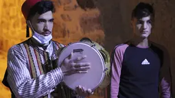 Pria Palestina yang dikenal dengan "Musaharatis" saat bertugas sebagai "penabuh drum Ramadhan" di kota tua Hebron, Tepi Barat pada 14 April 2021. Mereka menyusuri jalan-jalan kota, masuk ke gang-gang kecil untuk membangunkan umat Islam sahur selama bulan Ramadhan. (HAZEM BADER/AFP)