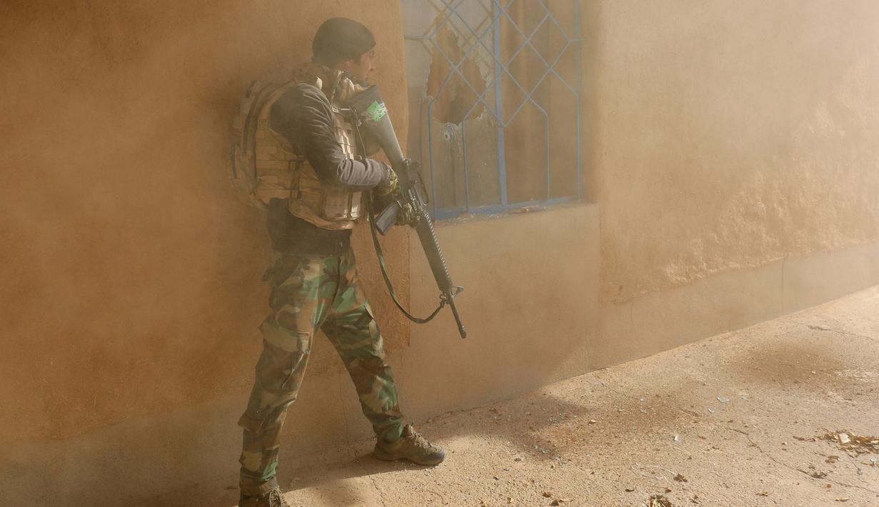 Seorang tentara Irak berlindung dibalik bangunan saat bertempur melawan militan ISIS di Al-Qasar, Tenggara Mosul, Irak, (28/11). (REUTERS/Goran Tomasevic)