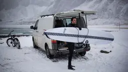 Seorang surfer membawa papannya bersiap berselancar di Unstad, Norwegia Utara (10/3). Surfer ini berselancar di wiliyah Lingkaran Arktik dengan suhu minus 13 derajat Celsius. (AFP Photo/Olivier Morin)