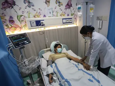 Tenaga kesehatan memeriksa kondisi salah satu pasien demam berdarah pada ruang perawatan pasien di RSUD Taman Sari, Jakarta Barat, Rabu (17/4/2024). (merdeka.com/Arie Basuki)