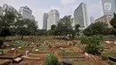 Pemandangan kompleks makam dengan latar belakang gedung-gedung bertingkat di TPU Karet Bivak, Jakarta, Kamis (12/7). DKI Jakarta saat ini memiliki lahan makam seluas 38,3 hektare, sementara 208,16 hektare belum siap pakai. (Merdeka.com/Iqbal Nugroho)