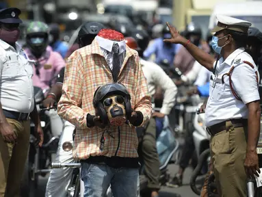 Petugas polisi bersama seorang sukarelawan (tengah) berpakaian seperti pengendara sepeda motor yang memegang kepala mockup dengan helm ambil bagian dalam kampanye kesadaran keselamatan jalan, di Chennai (7/7/2021). (AFP/Arun Sankar)