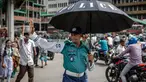 Seorang petugas polisi Bangladesh memegang payung untuk melindungi dirinya dari sengatan matahari saat mengatur lalu lintas di persimpangan jalan di Dhaka pada tanggal 12 Agustus 2024. (LUIS TATO/AFP)