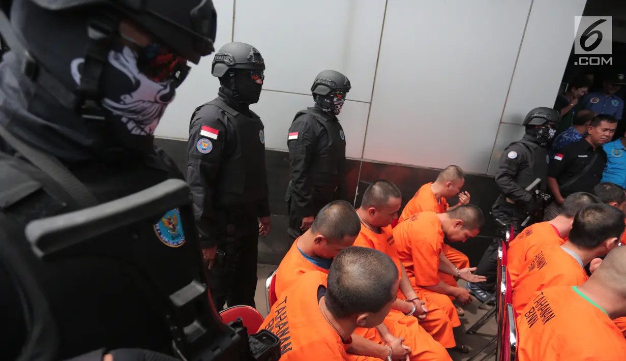 Polisi menjaga tersangka kasus penyelundupan narkoba oleh empat jaringan internasional di Kantor BNN, Jakarta, Selasa (10/10). Selain itu, 14 orang tersangka turut diamankan, tiga diantaranya ditangkap di beberapa lapas.(Liputan6.com/Faizal Fanani)
