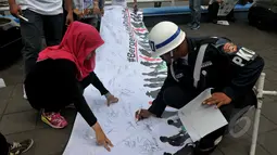 Warga yang melintas di kawasan Bundaran HI membubuhkan tanda tangannya saat aksi "Bergerak Untuk Disabilitas", Jakarta, Kamis (7/5/2015). (Liputan6.com/Johan Tallo)