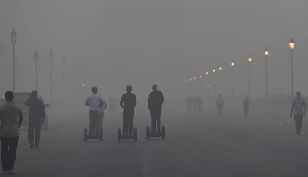 Pejalan kaki menyusuri jalan di tengah kondisi kabut asap tebal di New Delhi (2/11). Tingkat kabut melonjak selama musim dingin di Delhi, ketika kualitas udara melampaui tingkat aman Organisasi Kesehatan Dunia. (AP Photo/Money Sharma)