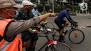 Satpol PP menegur pesepeda yang tidak mengenakan masker dengan benar di kawasan Bundaran HI, Jakarta, Minggu (17/1/2021). Pemerintah terus melakukan berbagai upaya guna mencegah penyebaran COVID-19 dan menurunkan angka masyarakat yang terpapar virus corona. (Liputan6.com/Johan Tallo)