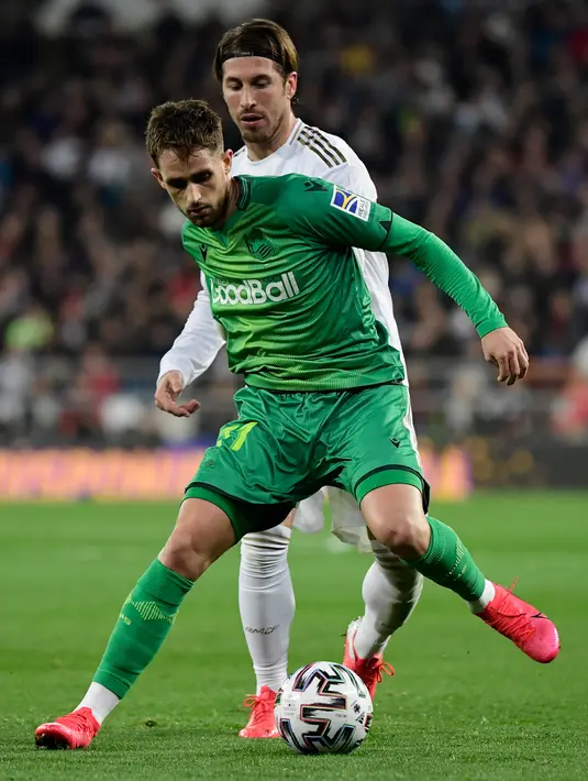 Bek Real Madrid, Sergio Ramos (kanan) berebut bola dengan pemain depan Real Sociedad, Adnan Januzaj pada laga perempat final Copa del Rey di Santiago Bernabeu, Kamis (6/2/2020). Real Madrid gagal melaju ke semifinal Copa del Rey setelah dibungkam Real Sociedad dengan skor 3-4. (JAVIER SORIANO/AFP)