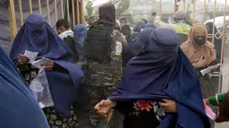 Seorang Taliban berjalan di antara orang-orang yang menunggu untuk menerima jatah makanan yang didistribusikan oleh kelompok bantuan kemanusiaan Korea Selatan, di Kabul, Afghanistan, Selasa (10/5/2022). Taliban pada Sabtu pekan lalu memerintahkan semua perempuan Afghanistan menutupi seluruh tubuhnya atau mengenakan burqa tradisional di depan umum. (AP Photo/Ebrahim Noroozi)