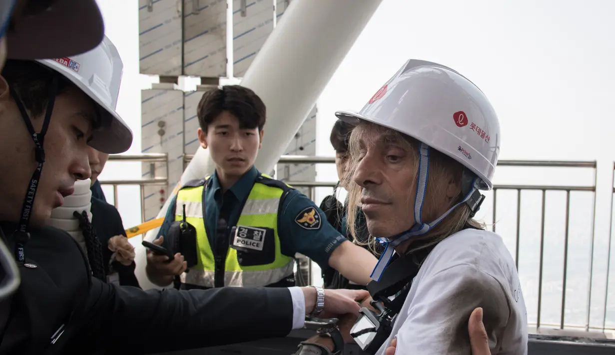 Urban climber atau pemanjat gedung, Alain Robert diamankan petugas setempat saat memanjat Menara Lotte World di Seoul, Korea Selatan (6/6). (AFP/Ed Jones)