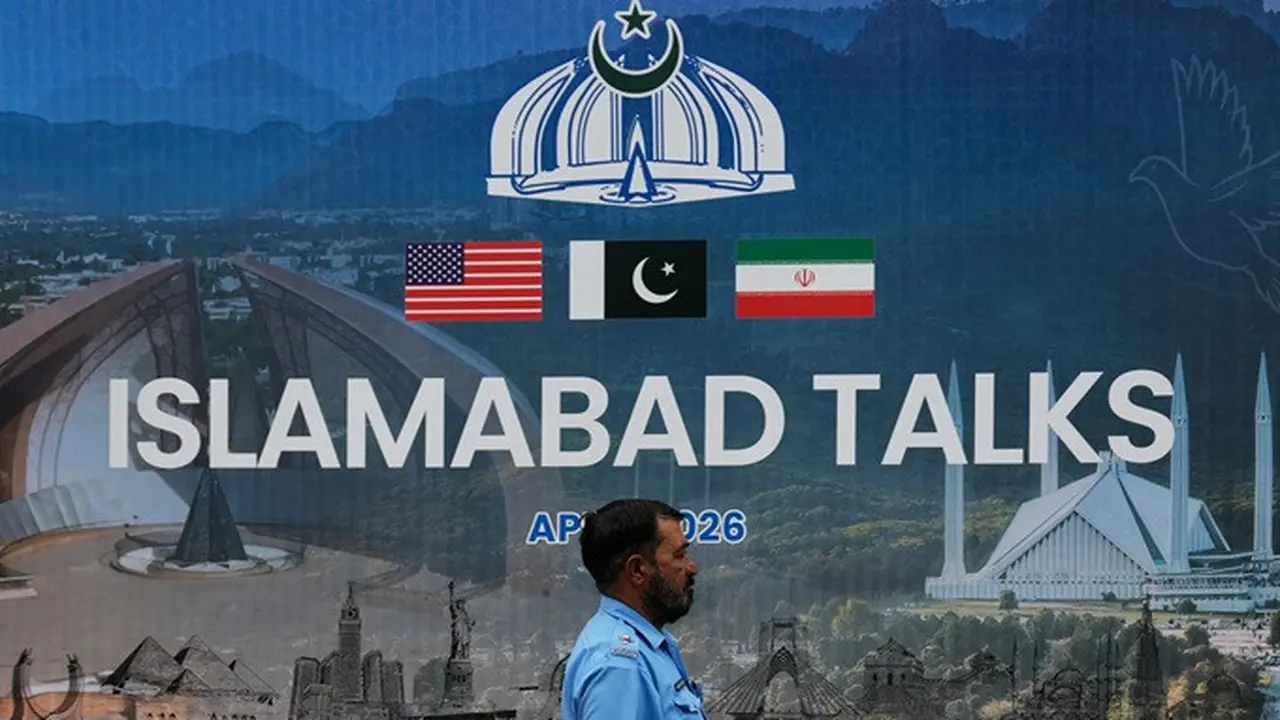 Seorang petugas polisi melintas di depan papan reklame tentang negosiasi antara Amerika Serikat dan Iran, di Islamabad, Pakistan, Sabtu (11/4/2026).