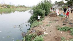 Seorang anak berusaha mengambil bola yang terjatuh ke kali Banjir Kanal Barat (BKB), Jakarta. Menjamurnya pemukiman dan gedung-gedung pencakar langit di Jakarta yang begitu cepat mengakibatkan lahan bermain anak menjadi korbannya. (bola.com/M Iqbal Ichsan)