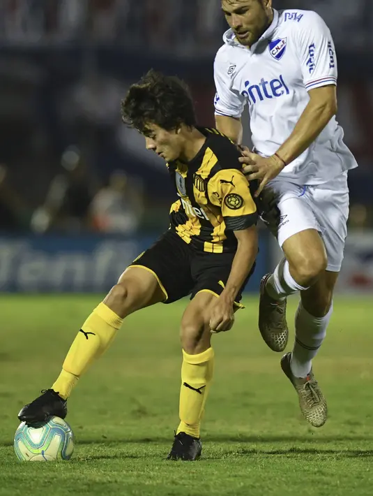 Gelandang Penarol, Facundo Pellistri mengontrol bola dari kawalan pemain Nacional, Rafael Garcia pada pertandingan final turnamen Uruguay Clausura di stadion Centenario di Montevideo, pada 11 Desember 2019. Facundo Pellistri didatangkan the Red Devils dari klub Uruguay Penarol. (AFP/Eitan Abramov