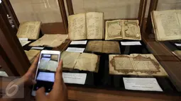 Pengunjung mengambil gambar sejumlah kitab yang dipajang saat pameran di Gedung PBNU, Jakarta, Senin (30/1). Pameran tersebut digelar dalam rangka Harlah NU ke-91. (Liputan6.com/Johan Tallo)
