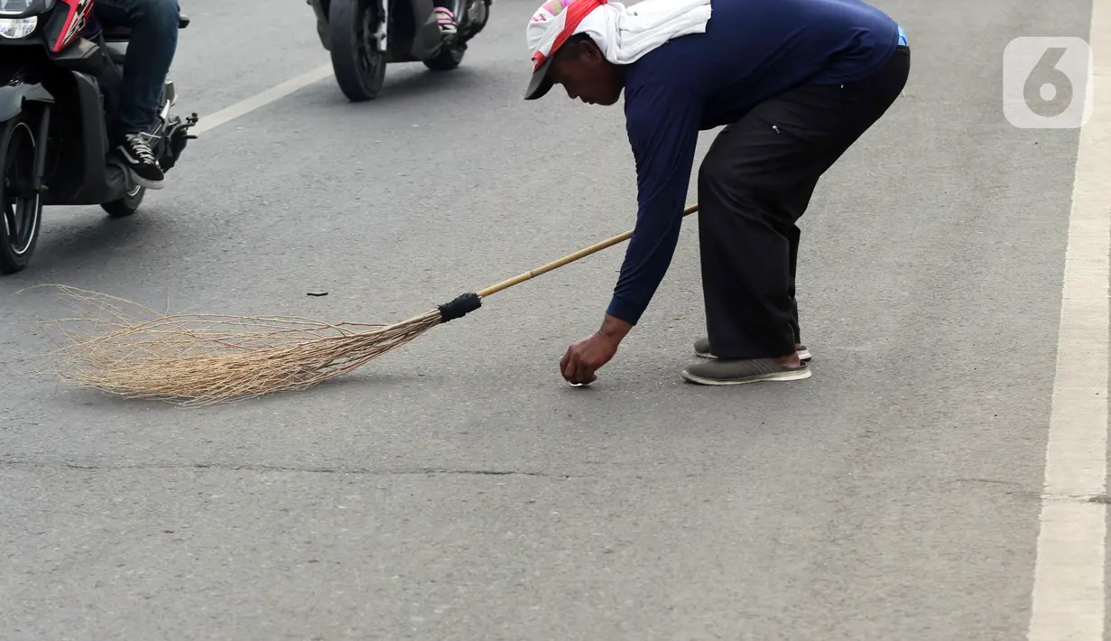 <p>Seorang warga mengambil sedekah pemberian pengendara kendaraan bermotor di kawasan Jembatan Sewo, Indramayu, Jawa Barat, Jumat (29/4/2022). Aksi mengambil uang sedekah menggunakan sapu meningkat saat puncak arus mudik. (Liputan6.com/Herman Zakharia)</p>