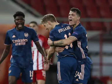 Gelandang Arsenal, Martin Odegaard (tengah) berselebrasi dengan rekannya usai mencetak gol ke gawang Olympiakos pada pertandingan leg pertama babak 16 besar Liga Europa di stadion Georgios Karaiskakis, Athena, Jumat (12/3/2021). Arsenal menang atas Olympiakos 3-1. (AP Photo/Thanassis Stavrakis)