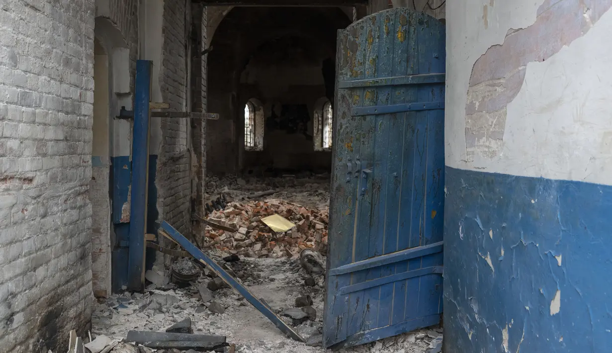 <p>Pintu masuk gereja yang rusak, di Lukashivka, Ukraina utara, 22 April 2022. Penduduk mengatakan tentara Rusia menggunakan rumah ibadah untuk menyimpan amunisi, dan pasukan Ukraina menembaki gedung itu untuk membuat Rusia pergi. (AP Photo/Petros Giannakouris)</p>
