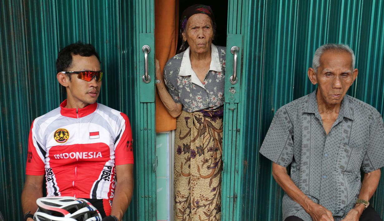 Pebalap sepeda Timnas Indonesia, Aiman Cahyadi beristirahat di teras toko warga saat berhenti di Barung-Barung Belantai dalam Etape 1 Tour de Singkarak 2015, Sabtu (3/10/2015). (Bola.com/Arief Bagus)