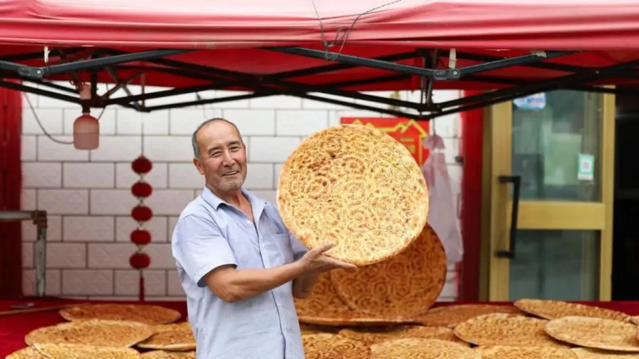 Rishit Himit menunjukkan roti naan buatannya di Kota Kuqa, Daerah Otonom Uighur Xinjiang, China, pada 21 Juli 2025 (Dok. ANTARA/Xinhua/Wang Jingqiang).