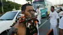 Seorang pemuja dari Kuil Samkong menusukkan senjata ke pipi saat memeriahkan festival vegetarian di Phuket, Thailand (17/10/2015). Festival ini menampilkan aksi ekstrem pemuja dengan menusukkan benda tajam ke wajah. (REUTERS/Jorge Silva)