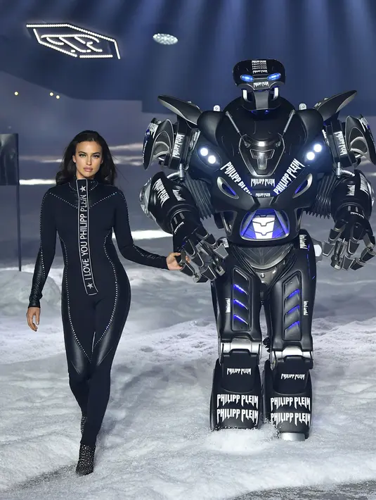 Model Irina Shayk bersandingan dengan robot saat mengenakan koleksi desainer Philipp Plein dalam New York Fashion Week 2018, Sabtu (10/2). Penampilan Irina juga disempurnakan dengan heels yang berhiaskan kristal. (Dimitrios Kambouris/GETTY IMAGES/AFP)