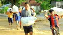 Warga membawa barang miliknya saat banjir bandang  di Kabupaten Bone Bolango, Gorontalo (11/6/2020). Data sementara yang diterima dari BPBD Kabupaten Bone Bolango sekitar 1.078 kepala keluarga serta 5.407 jiwa terdampak banjir bandang. (Liputan.com/Arfandi Ibrahim)