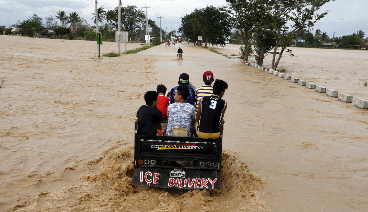 Sejumlah warga menaiki truk untuk melewati jalanan yang tertutup banjir yang disebabkan badai topan Koppu di Nueva Ecija,  Filipina, Senin (19/10/2015). Badai menyebabkan ratusan rumah hancur  dan 10.000 orang terpaksa mengungsi. (REUTERS/Erik De Castro)
