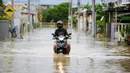 Seorang pria mengendarai sepeda motornya menerjang banjir di Batu Berendam, Malaka, Malaysia, 3 Januari 2022. Banjir besar masih terus menerjang negeri jiran Malaysia. (NAZRULHAD HASHIM/AFP)