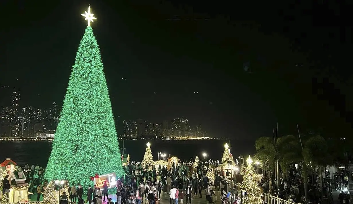 Orang-orang berkumpul pada Malam Natal di tepi Pelabuhan Victoria di Hong Kong, Jumat (24/12/2021). Sudut yang baru dikembangkan di Hong Kong, distrik budaya Kowloon Barat, menjadi daya tarik untuk Natal, orang-orang berkunjung untuk berfoto bersama keluarga dan teman-teman mereka. (AP Photo/Katie